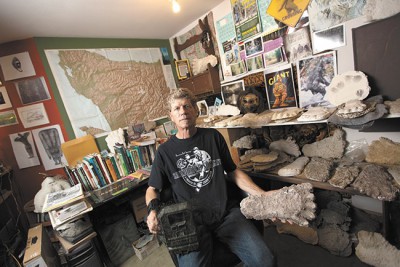 Paul Graves poses at his home in Wenatchee with an infrared camera and his collection of Sasquatch footprint casts. - YOUNG KWAK